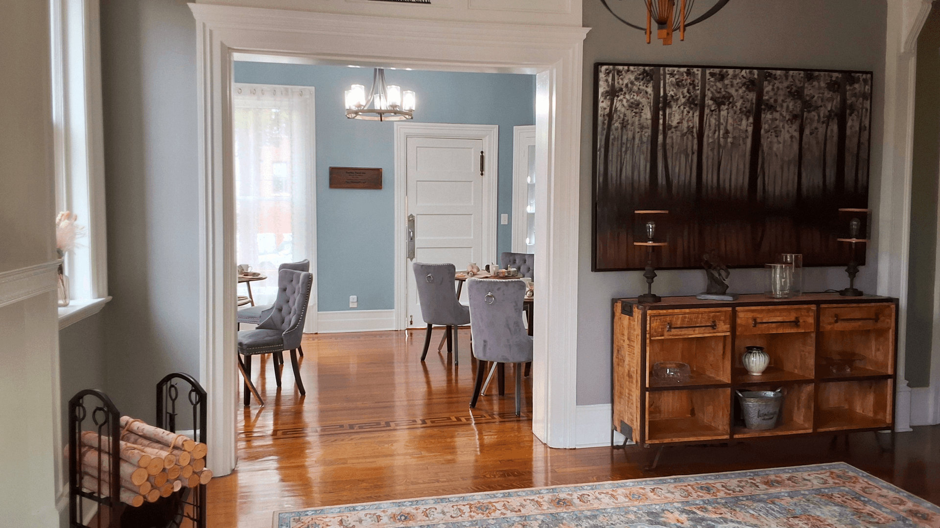 A view from a hallway into a stylish dining area featuring a wooden sideboard and elegant chairs.